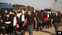 Des policiers de la frontière italienne escortent vers un centre de relocalisation des migrants subsahariens arrivés à bord du navire de sauvetage Golfo Azzurro au port d'Augusta, en Sicile, Italie, 23 juin 2017.