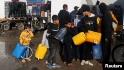 Anak-anak Palestina antre saat menunggu pengambilan air minum, di tengah kekurangan air minum, seiring berlanjutnya konflik antara Israel dan Hamas, di Rafah, Jalur Gaza selatan. 