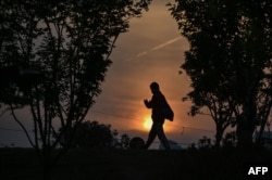 A man wearing a face mask walks at sunset in a park in Wuhan, in China's central Hubei province on April 19, 2020.