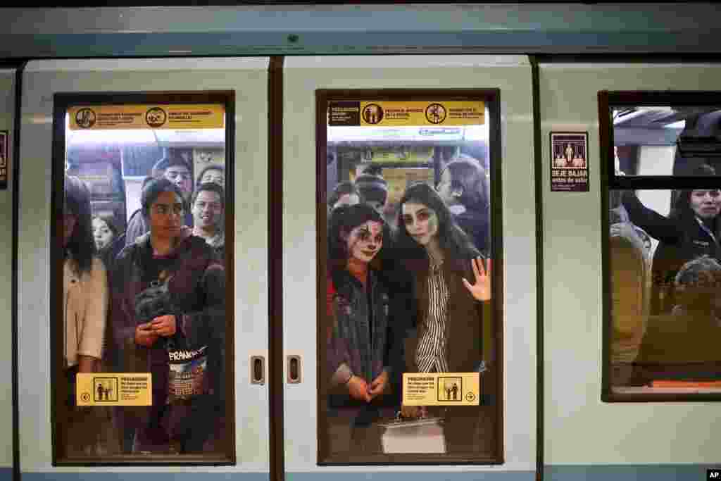 Two young women, with their faces painted for Halloween, travel in the subway in Santiago, Chile, Oct. 30, 2018.