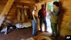 FILE - Ruth Toliner, left, and her husband Lowell Toliner, of Olney, Md., ask Steve Bashore questions about this newly reconstructed slave cabin at George Washington's Mount Vernon estate in Mt. Vernon, Va, Sept. 19, 2007. Scholastic Publishing is recalling one of its children's books from bookstore shelves in the U.S as it may give a false impression of the reality of the lives of slaves.