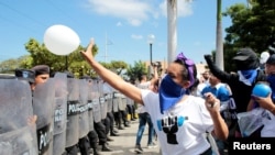 Una manifestante lanza un globo a la policía antidisturbios durante la conmemoración del Día Internacional de los Derechos Humanos en Managua, Nicaragua el 10 de diciembre de 2019.