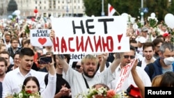 People take part in an opposition demonstration to protest police violence and to reject the presidential election results in Minsk, Belarus, Aug. 14, 2020. The placard reads: "No to violence". 