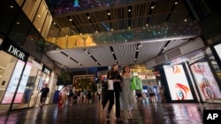 FILE - People shop at Taikoo Li Sanlitun in Beijing, China, July 2, 2024. 