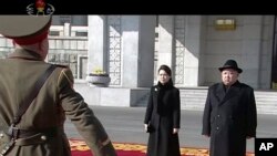 Un militaire salue le leader nord-coréen Kim Jong Un et sa femme Ri Sol Ju, lors d'une parade militaire a Pyongyang, Corée du Nord, le 8 février 2018.