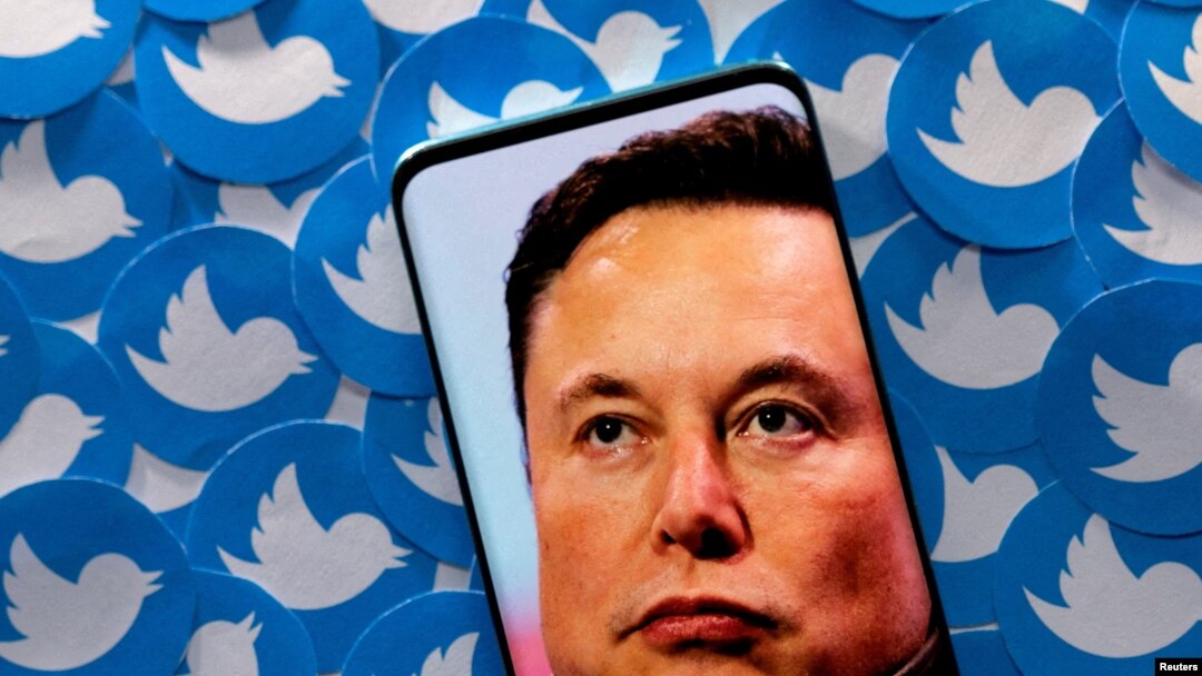 Foto ilustrasi yang diambil pada 28 April 2022 ini menunjukkan gambar wajah Elon Musk pada layar sebuah telepon genggam yang ditaruh di depan sekumpulan logo platform Twitter yang telah dicetak. (Foto: Reuters/Dado Ruvic)
