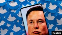 Foto ilustrasi yang diambil pada 28 April 2022 ini menunjukkan gambar wajah Elon Musk pada layar sebuah telepon genggam yang ditaruh di depan sekumpulan logo platform Twitter yang telah dicetak. (Foto: Reuters/Dado Ruvic)