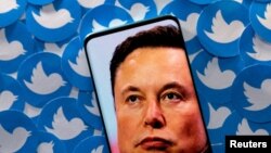 FILE PHOTO: Illustration shows Elon Musk image on smartphone and printed Twitter logos