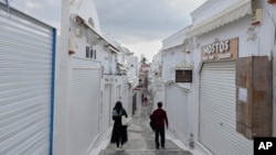 Tourists pass by closed shops in Fira town as Greek authorities are taking emergency measures in response to intense seismic activity on the popular Aegean Sea holiday island of Santorini, southern Greece, Feb. 3, 2025.