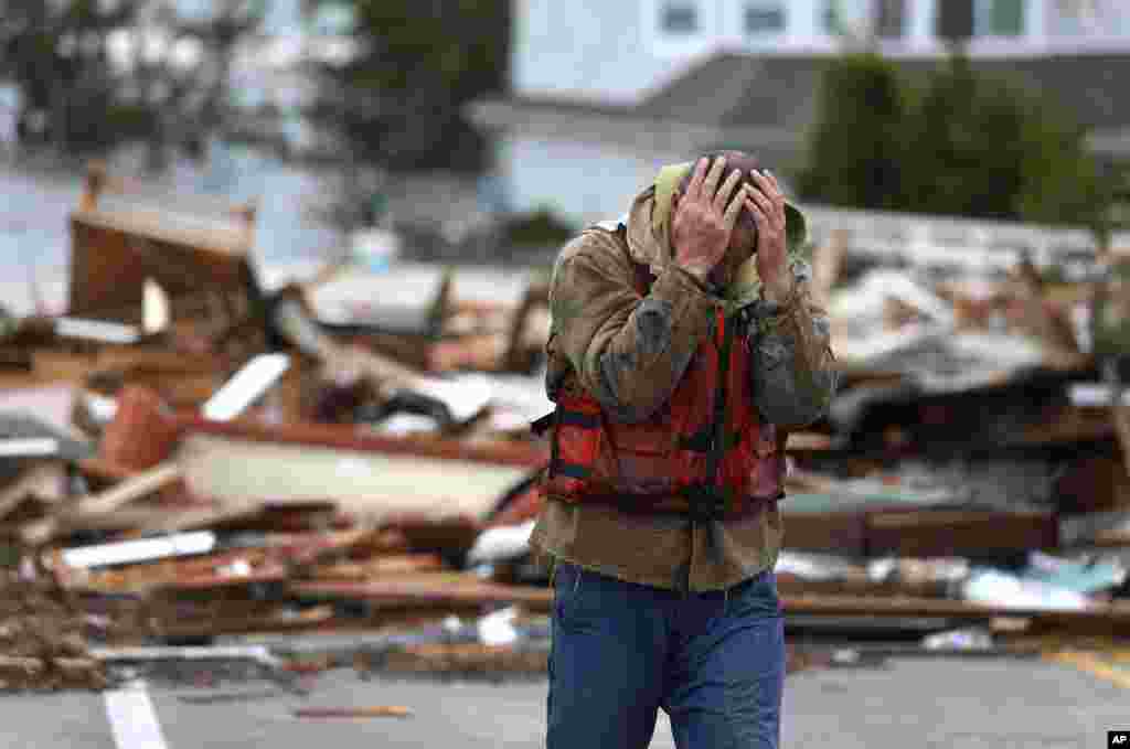 Brian Hajeski, 41, dari Brick, New Jersey, menutup wajahnya setelah melihat reruntuhan rumahnya yang disapu sampai Jembatan Mantoloking Bridge pada pagi hari setelah badai super Sandy melanda Mantoloking, New Jersey (30/10).&nbsp; 