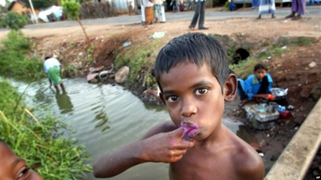 Một bé trai Sri Lanka đánh răng bằng nước từ con kinh