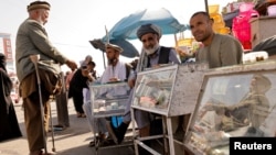 Sejumlah pria Afghanistan duduk di belakang kios penukaran mata uang mereka di Kabul, Afghanistan 7 Oktober 2021. (Foto: REUTERS/Jorge Silva)