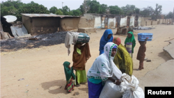 A woman packs up what is left of her family's belongings after an attack by Boko Haram insurgents in Kawuri, Nigeria, Jan. 28, 2014.