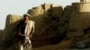 An Afghan man rides his bicycle through an old city area of Ghazni province, 20 August 2007. 