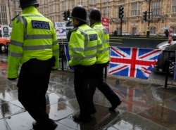 Three policemen patrol past various Brexit flags and banners outside the Houses of Parliament in London, April 2, 2019.
