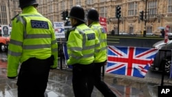 Three policemen patrol past various Brexit flags and banners outside the Houses of Parliament in London, April 2, 2019. 
