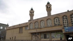 FILE - In this Feb. 20, 2019 photo, an Afghan boy walks past the Jawadia Shi'ite mosque that was targeted by by Islamic State gunmen the previous year, killing 38 people, in Herat, western Afghanistan.