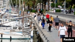 People walk on the Palma de Mallorca sea promenade during hours in which individual exercise is now permitted outdoors, for the first time since Spain went on a nationwide coronavirus lockdown, in Palma de Mallorca, Spain, May 2, 2020. 