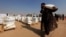 A displaced woman, who fled from Mosul due to Islamic State violence, carries food in Khazer refugee camp, east of Mosul, Iraq, Nov. 7, 2016. 