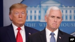 President Donald Trump, left, listens to Vice President Mike Pence, right, as he pauses while speaking to members of the media to address the nation about the coronavirus threat.