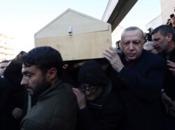 Turkey's President Recep Tayyip Erdogan carries the coffin of a victim after an earthquake hit Elazig, eastern Turkey, Friday, during the funeral procession for Salih Civelek and Aysegul Civelek, Jan. 25, 2020.