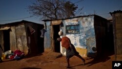 A South African woman, bounces the ball on her head while playing with a football next to their homes in a Soweto, township on the outskirts of Johannesburg, July 4, 2013.