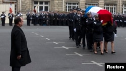 French President Francois Hollande looks at a coffin as he attends a national tribute at Paris Prefecture for the three officers killed during last week's attacks by Islamic militants, Jan. 13, 2015. 