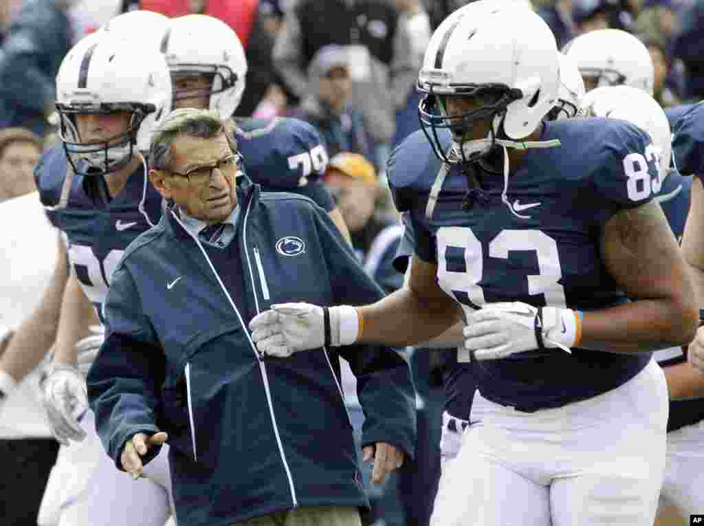 Penn State head coach Joe Paterno, left, gets out of the way of tight end Nate Cadogan (83) during warm-ups before an NCAA college football game against Purdue in State College, Pa., October 15, 2011 (AP)