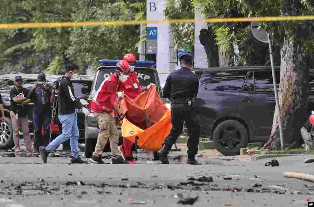 Police officer and rescue workers carry a body bag containing what is believed to be human remains outside a church where an explosion went off in Makassar, South Sulawesi, Indonesia.&nbsp;A suicide bomber blew himself up outside a packed Roman Catholic cathedral during a Palm Sunday Mass, wounding a number of people, police said.&nbsp;