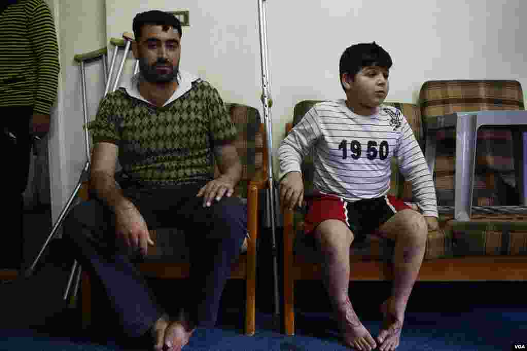 A wounded Syrian rebel sits beside a boy in Amman, Jordan. &nbsp;The boy was hurt in a missile strike on his home in Dara, Syria. (Y. Weeks/VOA)