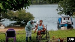 Un trabajador de salud del Departamento de Salud Indígena del Ministerio de Salud administra una segunda dosis de la vacuna COVID-19 a una mujer en la aldea Esperanca do Rio Arapiun, febrero 14 de 2021.