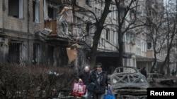 Los residentes locales dejan su edificio de apartamentos, dañado durante un ataque con misiles rusos, en medio del ataque de Rusia a Ucrania, en Kiev, Ucrania, el 13 de diciembre de 2023.