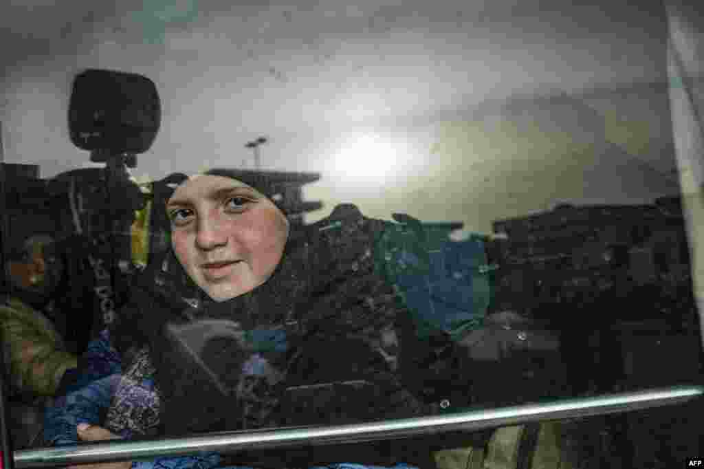 A child sits in a bus during the handover of orphaned children, whose parents were suspected of belonging to the Islamic State group, to a Russian delegation by Syrian Kurdish officials, at the headquarters of the department for foreign affairs of the semi-autonomous Kurdish administration in Syria&#39;s northeastern city of Qamishli, April 18, 2021.