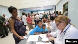 FILE - A doctor assists people looking for treatment for malaria at a health center in San Felix, Venezuela, Nov. 3, 2017. 