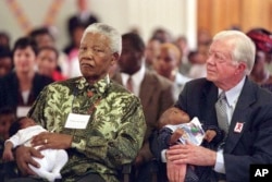 FILE - Former South African President Nelson Mandela, left, and former US President Jimmy Carter hold HIV-positive babies at the Zola Clinic in Soweto, March 7, 2002.