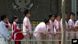 FILE -- In this May 2012 file photo, Chinese students wait outside the U.S. Embassy for their visa application interviews in Beijing, China. 