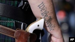 FILE - Scott Smith, a supporter of open carry gun laws, wears a pistol as he prepares for a rally in support of open carry gun laws at the Capitol in Austin, Texas, Jan. 26, 2015. 