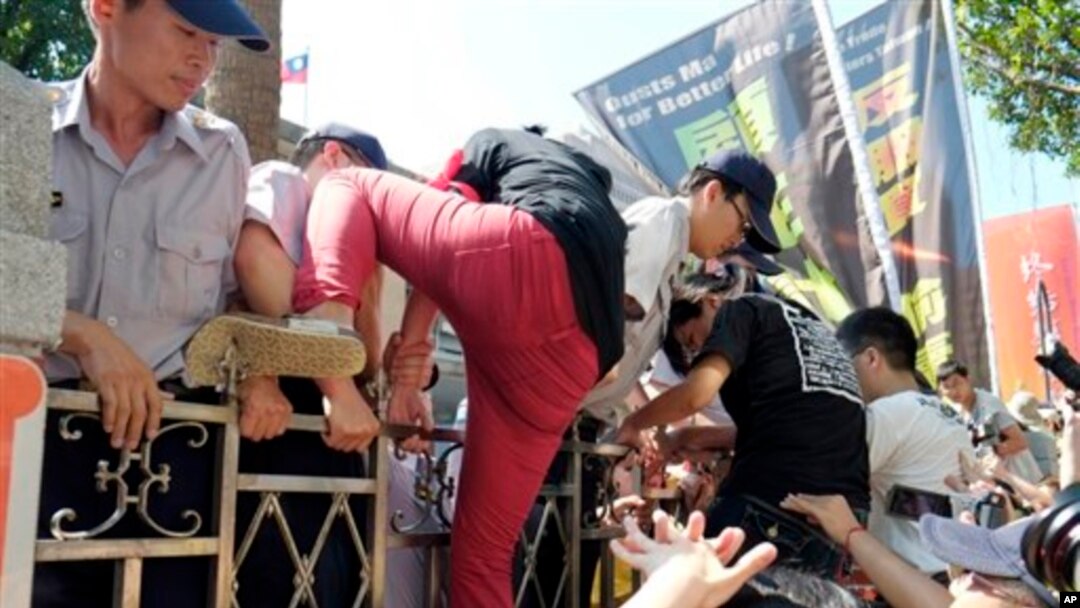 Polisi mendorong demonstran yang berupaya memanjat pagar gedung badan legislatif Taiwan dalam aksi demo anti-perjanjian perdagangan Taiwan-China di Taipei, Taiwan (31/7).