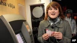 An Estonian woman holds one of the new Euro banknotes which she has just withdrawn from an ATM cash machine in Tallinn, Estonia, 01 Jan 2011.