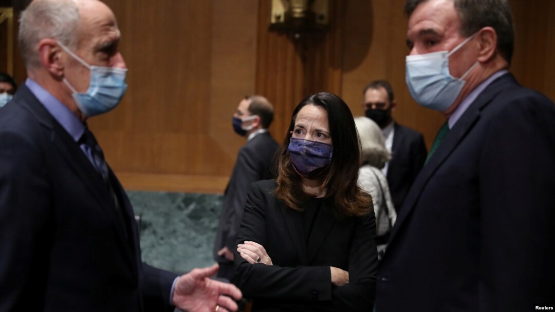 Avril Haines (tengah) bersama Dan Coats (kiri), mantan Direktur Intelijen Nasional AS dan Senator Mark Warner, di Washington DC, 19 Januari 2021. (Joe Raedle/Pool via REUTERS)