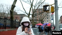 A woman wearing a face mask looks at her phone in Chinatown in the Manhattan borough of New York City, Jan. 25, 2020.