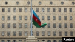 A bandeira do Estado azeri é hasteada a meia haste enquanto o país observa o dia de luto nacional pelas vítimas do acidente de um avião de passageiros Embraer da Azerbaijan Airlines, no exterior da Casa do Governo em Baku, Azerbaijão, 26 de dezembro de 2024.