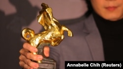 Seorang artis menunjukkan piala Golden Horse (Kuda Emas) dalam ajang penghargaan film 58th Golden Horse Awards di Taipei, Taiwan, Sabtu, 27 November 2021. (Foto: Annabelle Chih/Reuters)