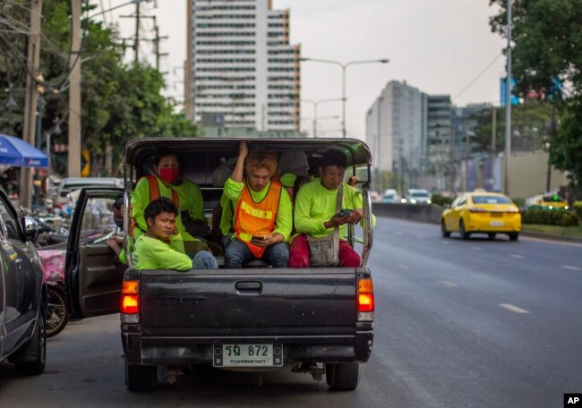 Pekerja konstruksi migran, sebagian mengenakan masker di tengah pandemi corona, berdesakan di dalam truk usai jam kerja di Bangkok, Thailand, 9 April 2020.