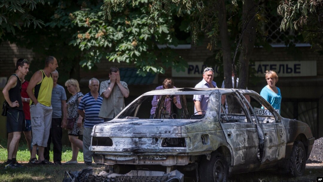 Abantu bariko bararaba imodoka yarashwe n'indege z'igisiriikare c'igihugu ca Ukraine mu gisagara ca Slovyansk, muri Ukraine, kw'igenekerezo rya 28 ry'ukwezi kwa gatanu, umwka w' 2014. 