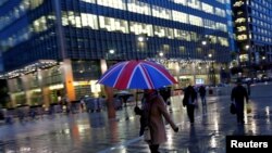 Para pekerja berjalan di tengah hujan di kawasan bisnis Canary Wharf di London, Inggris. (Foto:dok)