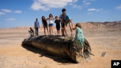 (FILE) People climb on the debris of an Iranian missile intercepted by Israel, near Arad, southern Israel, Oct. 2, 2024. 