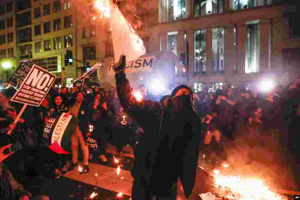 واشنگٹن میں ٹرمپ مخالف مظاہرے کے دوران ایک شخص پلے کارڈ جلا رہا ہے۔