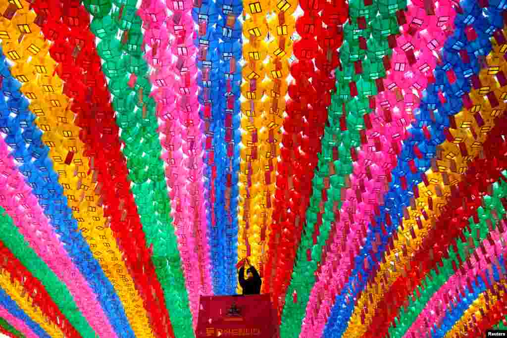 A worker wearing a protective face mask during the coronavirus disease (COVID-19) outbreak, attaches prayer petitions, with names written on cards, to lotus lanterns in preparation of the upcoming birthday of Buddha at a temple in Seoul, South Korea.