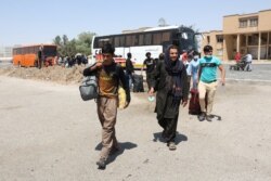 FILE - Afghans walk at the Dowqarun border crossing between Iran and Afghanistan, Razavi Khorasan Province, Iran, August 29, 2021.